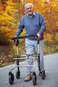快乐的有行走残疾的老人在秋天公园散步推着她的图片