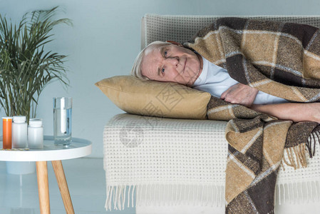 在沙发上睡着的长身盖满格子的老年病人躺在沙发上的房间里图片