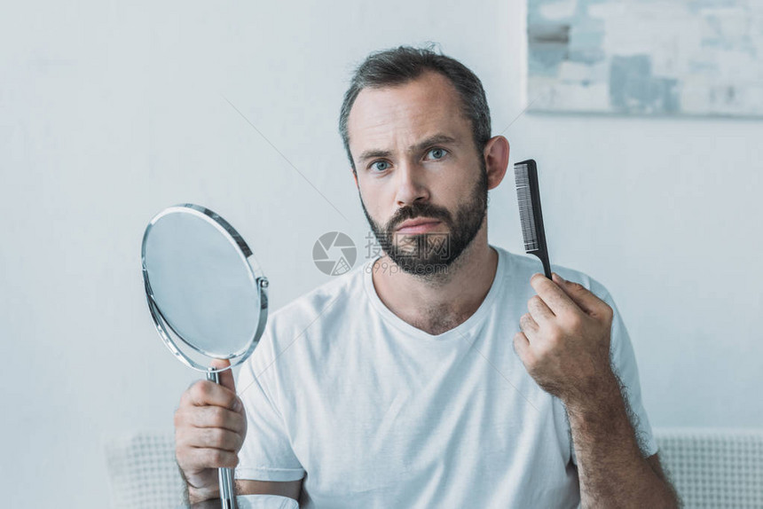 中年男子用梳子照镜子看照相机图片