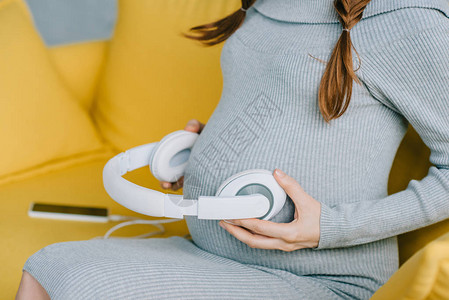 孕妇将带音乐的耳机放在客厅腹图片