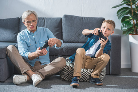 祖父和孙子用操纵杆玩电子游戏图片