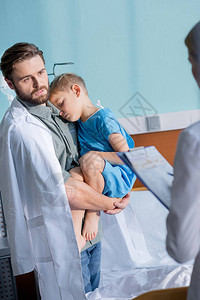 年轻父亲在医院看医生时抱着小儿图片