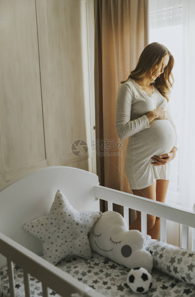 房间里摇篮旁的漂亮年轻孕妇图片