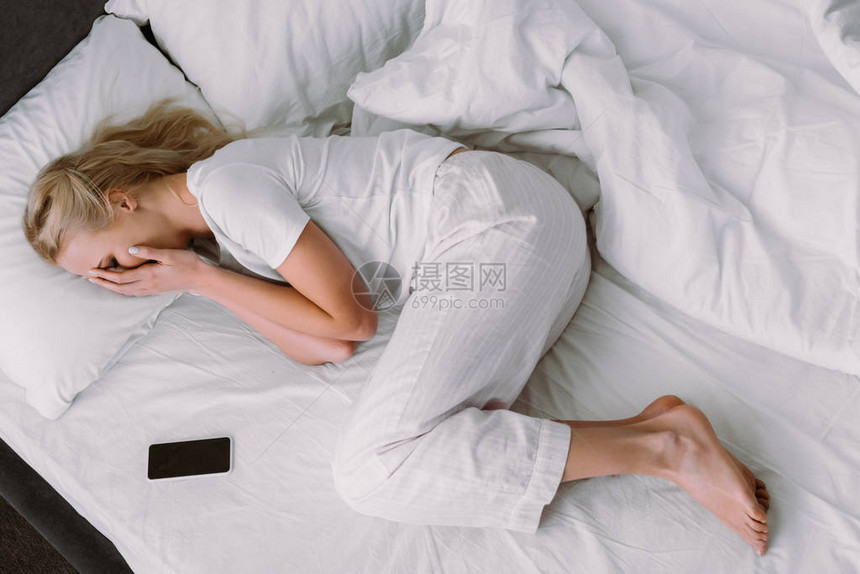 妇女躺在近智能手机附近时图片