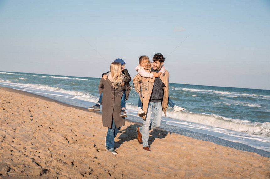 在海滩上共度时光的同时带着孩子的快乐父母们一图片