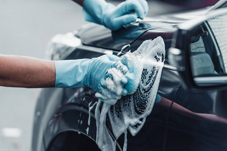 用海绵和洗涤剂洗车的汽车清洁剂的裁剪视图图片