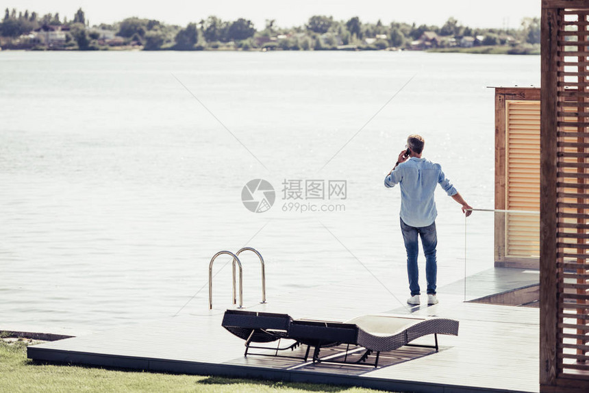 成年男子在乡村小屋湖边用智能手机说图片