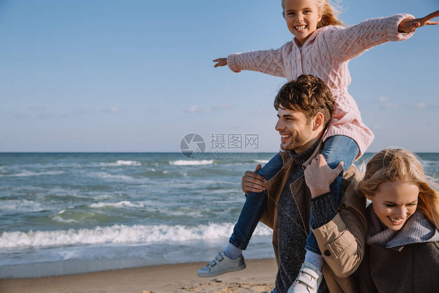 秋天一家人带着快乐的女儿在海边散步图片