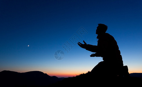 人在日落时分在山顶上祈求上帝图片