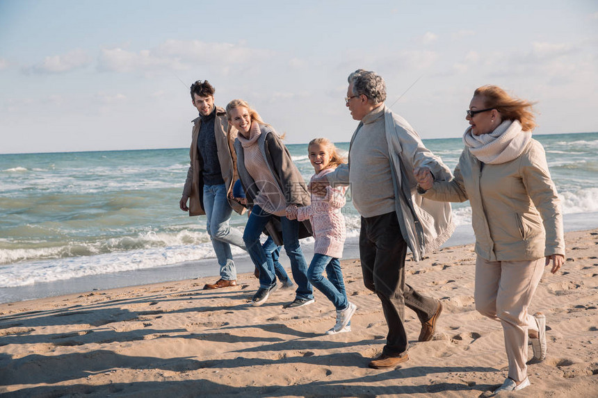 多代人大家庭在海边滩上手牵并一起奔图片