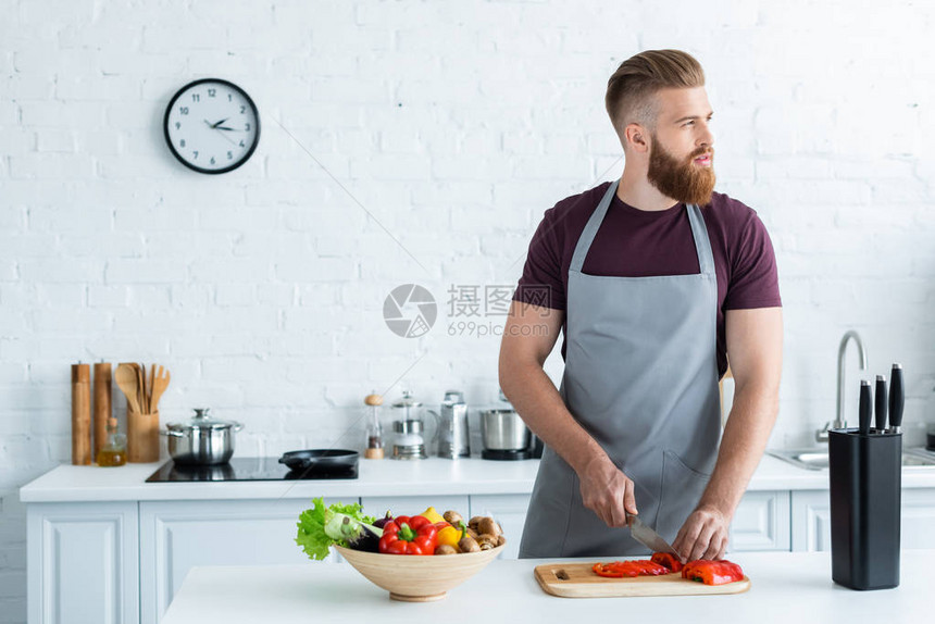 穿着围裙的英俊长胡子青年男子在厨房图片