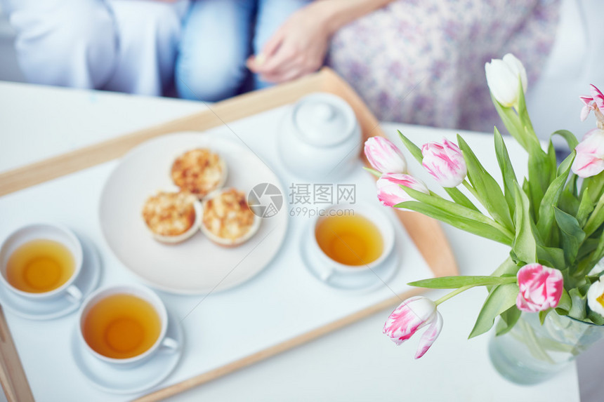 花瓶里新鲜的郁金香茶叶草药和松饼放在图片