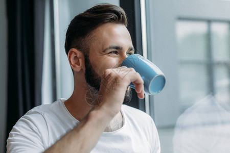 英俊的年轻男子喝茶从杯子喝茶图片