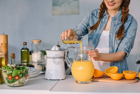 孕妇在厨房往壶里倒橙汁的裁剪图像图片