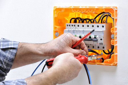 在住宅电板上工作的电工技师图片