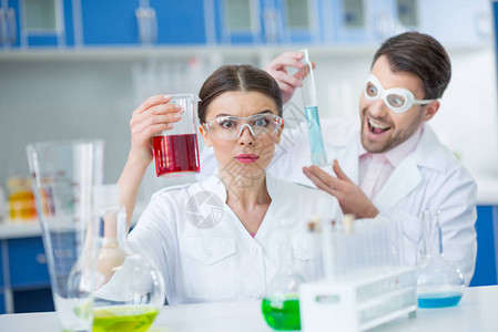 在实验室与试剂一起工作的身戴保护眼镜的激动人心的男科学图片