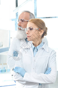 身穿白大衣和护目镜的两名科学家向外看图片