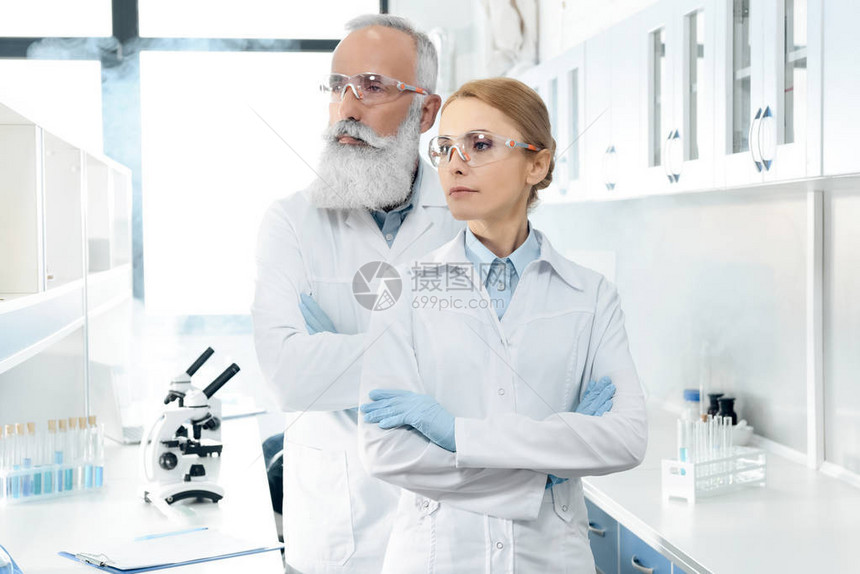 身穿白色大衣和护目镜的两名有自信的科学家向外看图片
