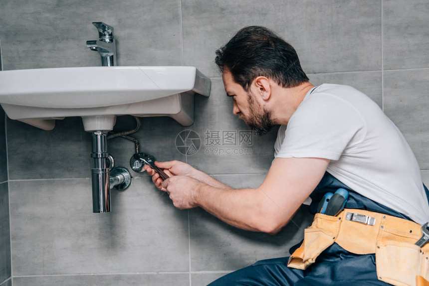 男水管工在洗手间用打手总固定水槽工作图片
