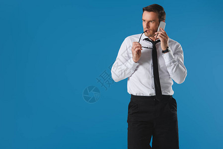 男人在用智能手机说话时咬眼镜看着孤图片