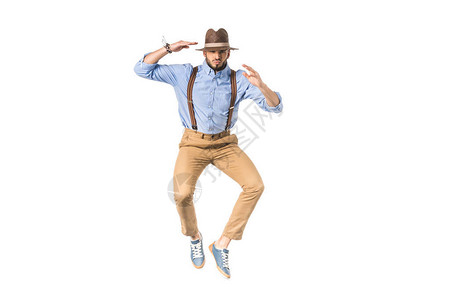 时尚的年轻男子在帽子跳跃和看镜头图片