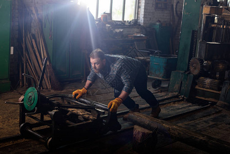 在锯木厂戴防护手套推机器的工人图片