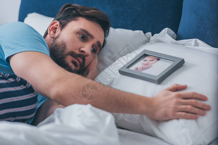 男人躺在床上在家里靠着枕头的女人的照图片