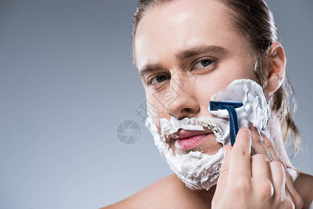 白种人用泡沫擦脸手握剃刀在图片