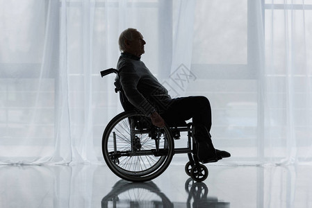 窗前坐轮椅的体贴老人背景图片