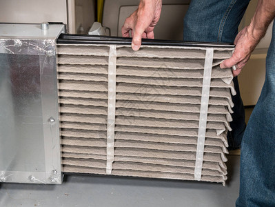 在家庭地下室的HVAC锅炉系统中更换一个折叠脏空气过滤器的高图片