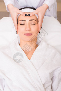 在美容院给睡在浴袍和发带上的女人做工脸部按图片
