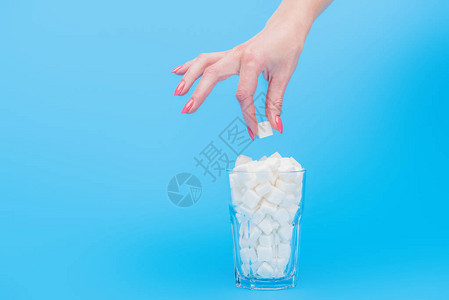 女将糖的立方体放在玻璃周围满是白糖的一图片