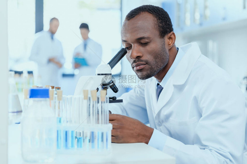 身穿白大褂的非洲裔美国科学家在实验室用显微镜工作图片