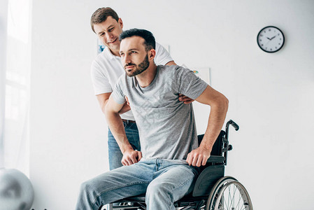 在医院康复期间帮助轮椅残疾人康复的理疗师图片