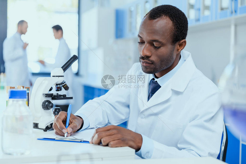身穿白大褂的非洲裔美国科学家在实验室工作时记笔图片