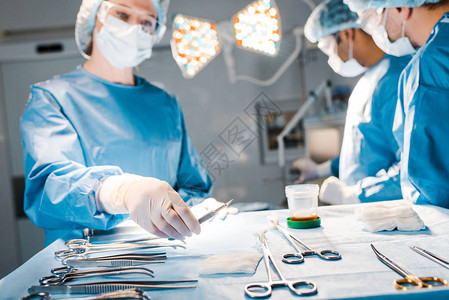 医生有选择地重点进行手术和护士穿制服和医用帽子图片