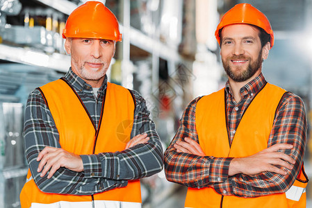 2名男工人身着安全背心和安全头盔图片