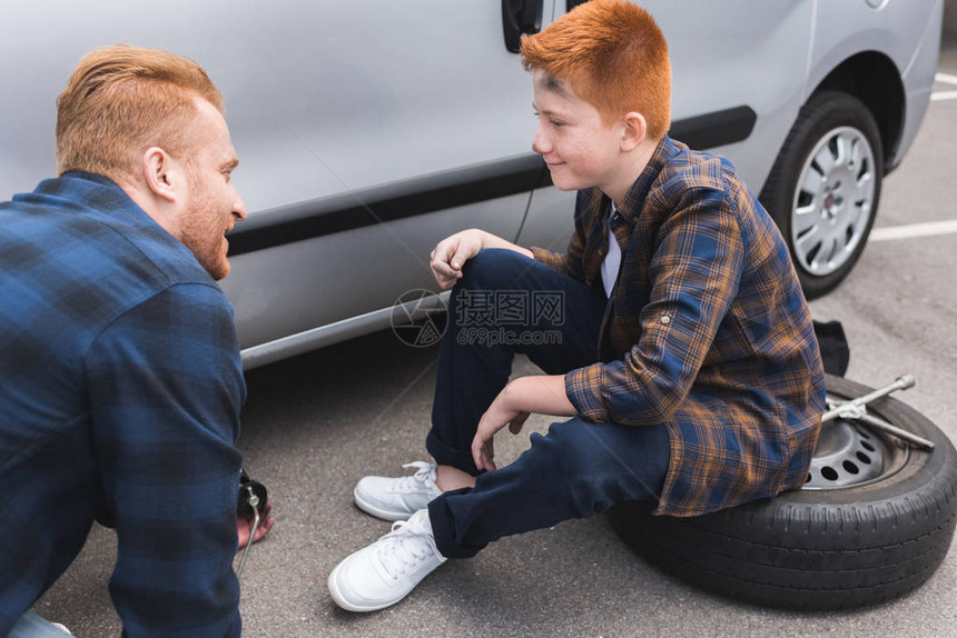 父亲和儿子在汽车里换车胎用一地板图片