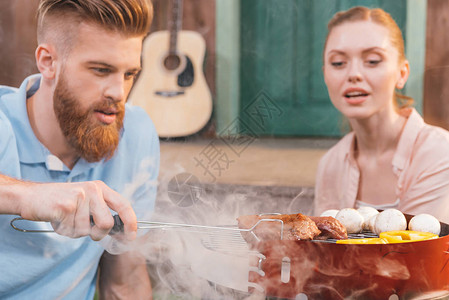 男人和女人在烤肉架上烤肉和蔬菜图片