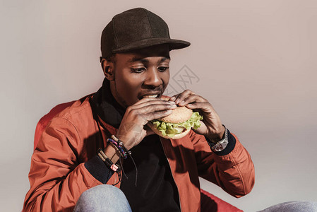 美国人吃汉堡包的年轻非洲男子孤图片