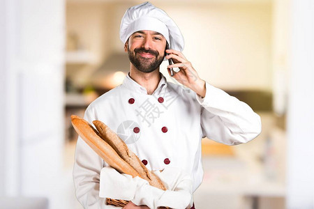 年轻面包师拿着面包在厨房图片