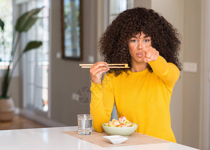 在家吃亚洲米饭的非洲裔美国妇女用手指着相机和你图片