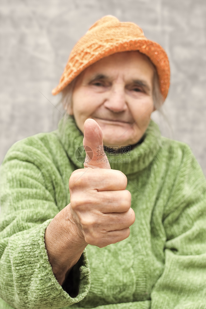 老年妇女大拇指举起手来作为认图片