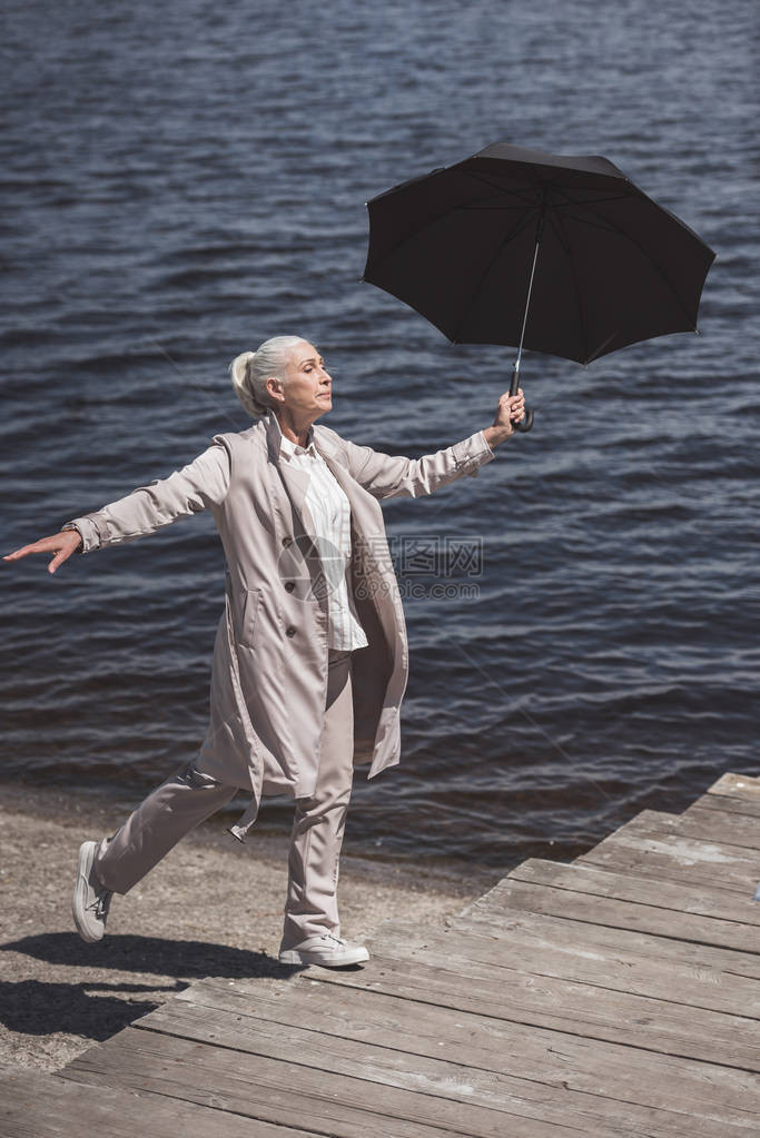 白天在河岸边带雨伞的年长图片