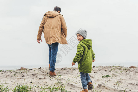 秋日阴天父子在沙滩上散步的背影图片