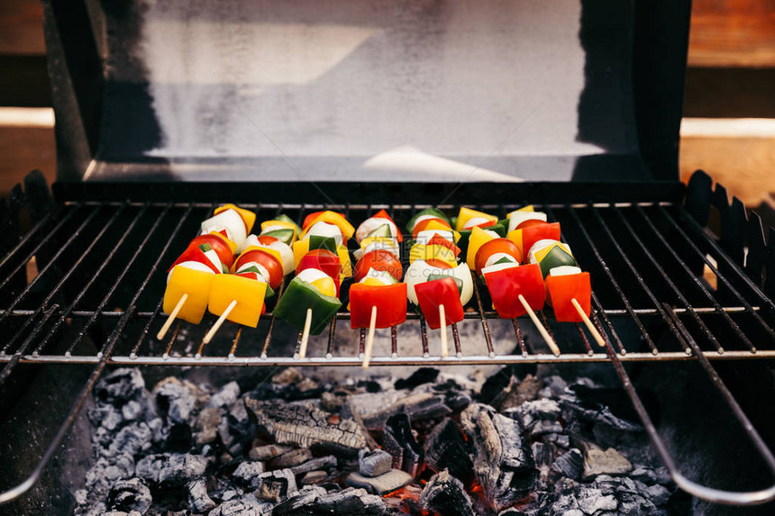 木串上的蔬菜在户外烤架上用火烤图片