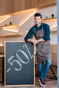 面带微笑的服务员站在黑板附近咖啡馆售背景图片