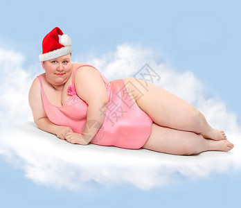 穿着圣诞老人帽子的肥胖女人在天堂飘浮在云上圣诞节贺图片