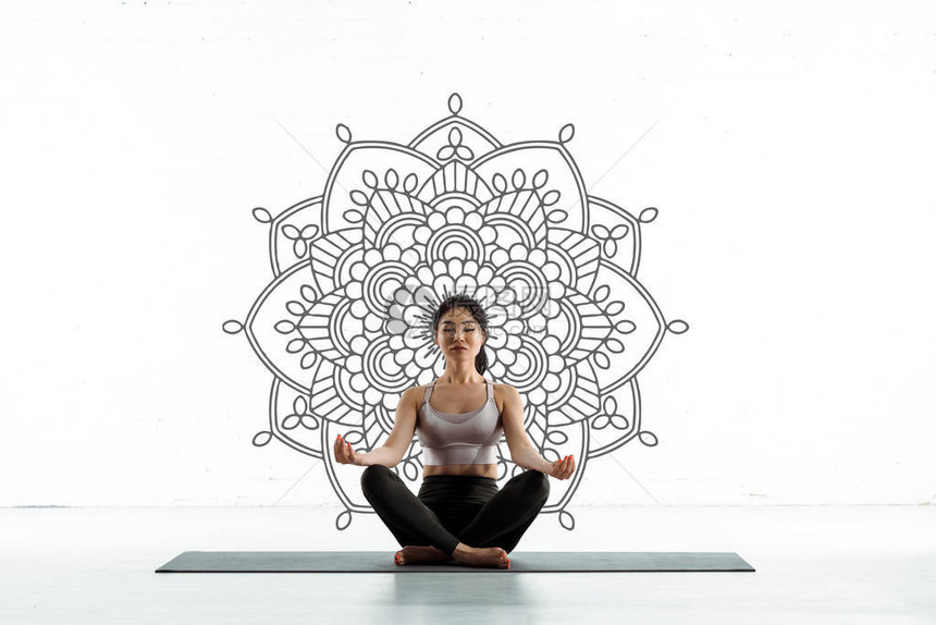 平和的泰女在瑜伽垫上做瑜伽在曼达拉白图片