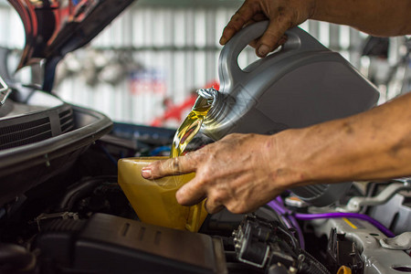 汽车修理工在车库填充新鲜的润滑油发动机图片